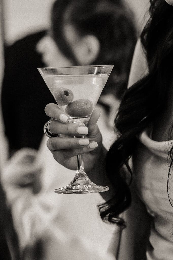 Black and white close up shot of a guest holding a martini.