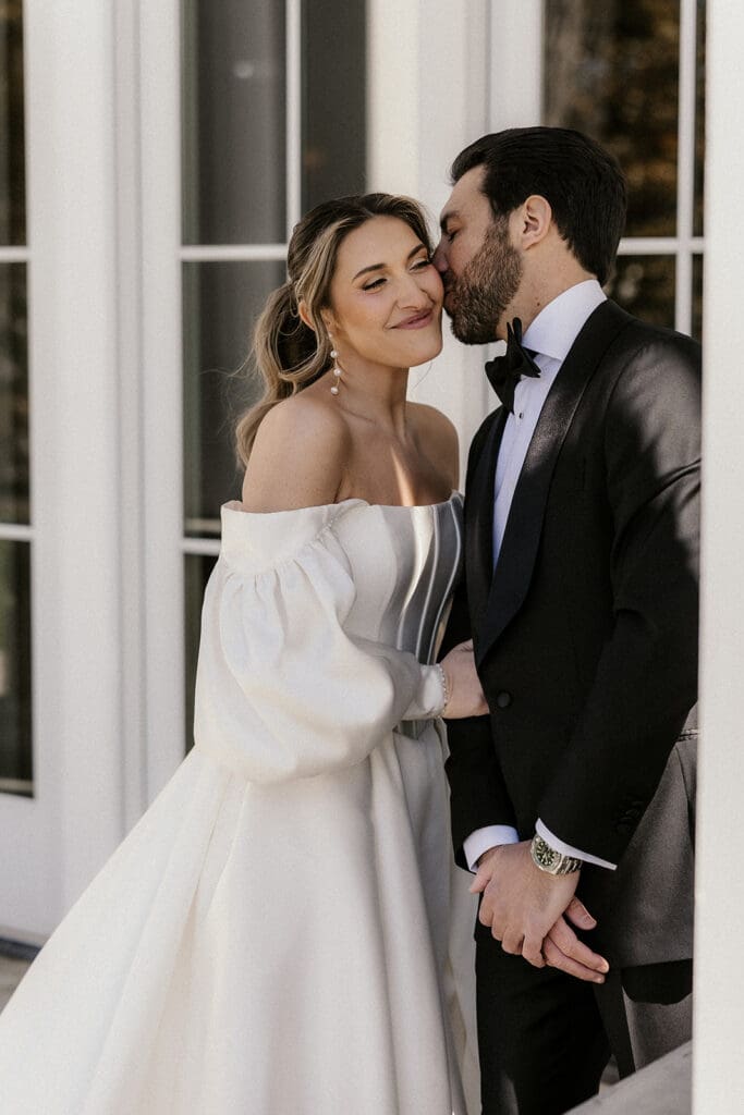 Groom kissing the brides cheek during portraits at The Rylan Inn wedding venue in White House Station, NJ.