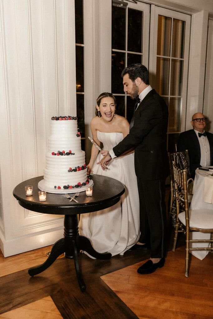 Bride and groom cutting into their four-tiered wedding cake.