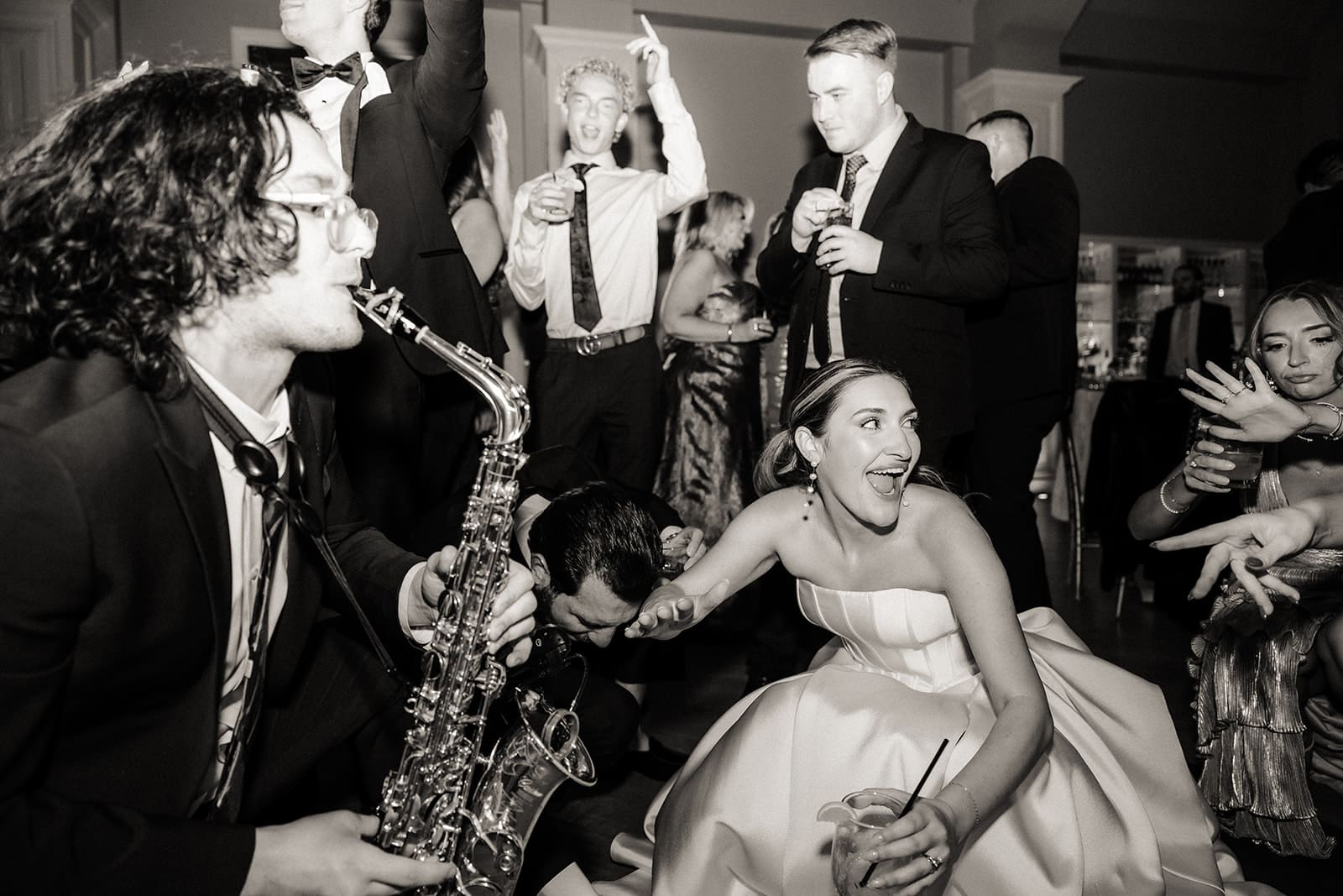 Bride dancing with guests and saxophone player during The Ryland Inn wedding reception.