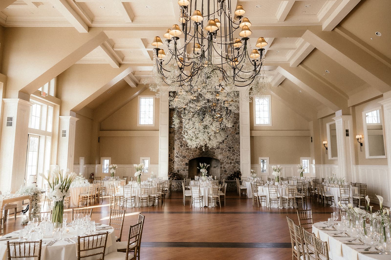 Grand Ballroom reception setup at The Ryland Inn with white florals and gold chairs.
