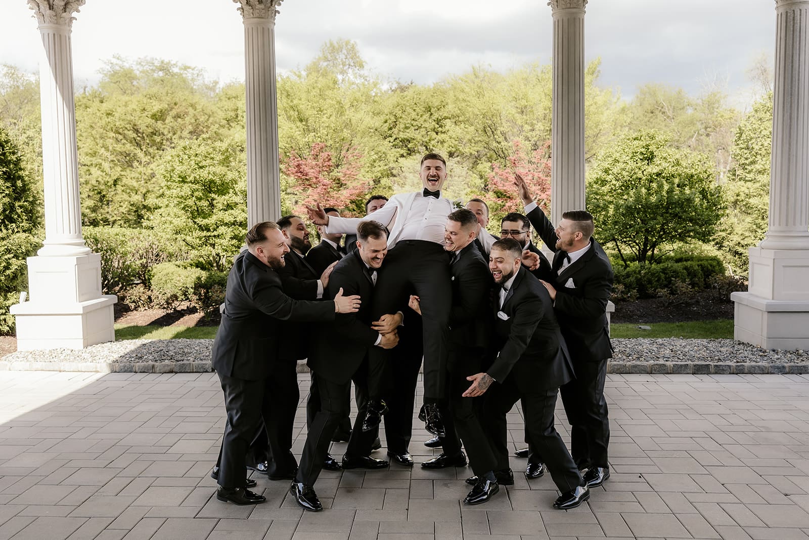 Groomsmen lifting up the groom during bridal party photos.