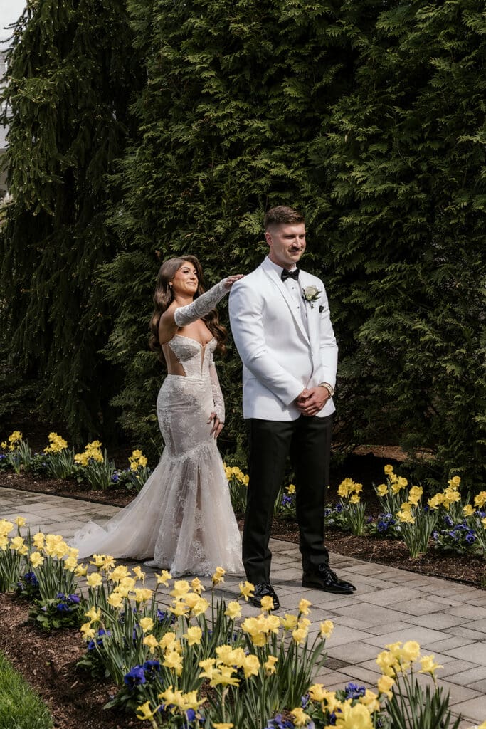 Bride tapping the groom on his shoulder during their first look in the garden area at The Palace at Somerset Park.