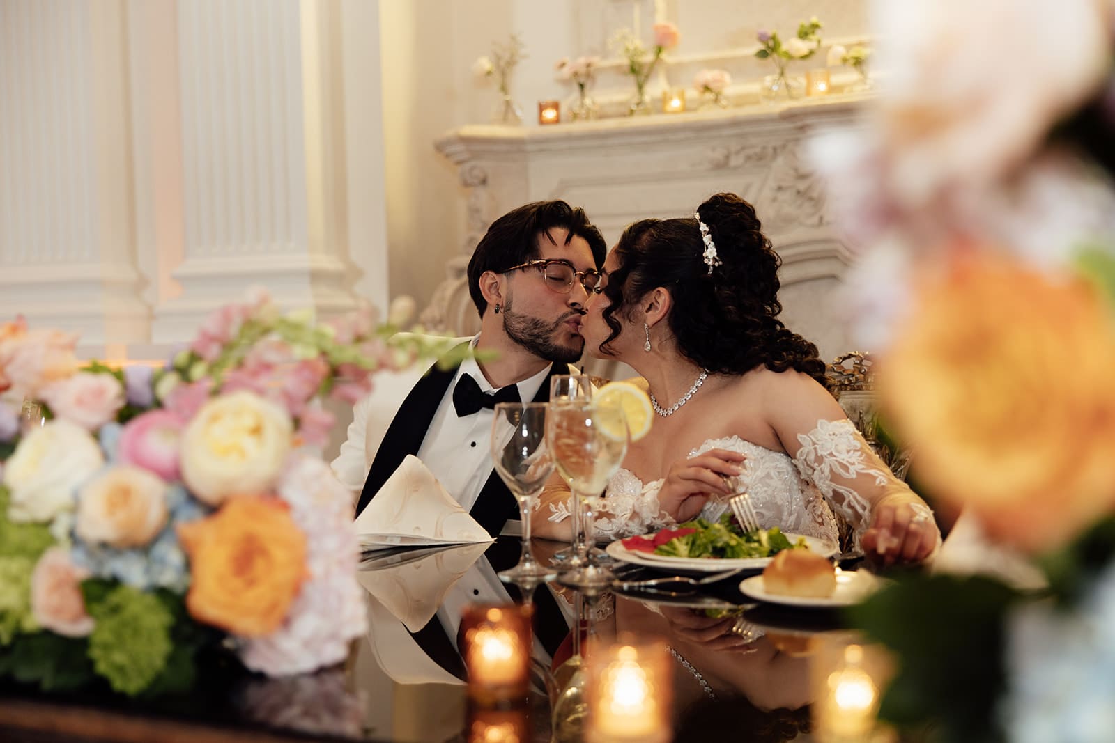 Bride and groom kissing at their sweethearts table during their reception.