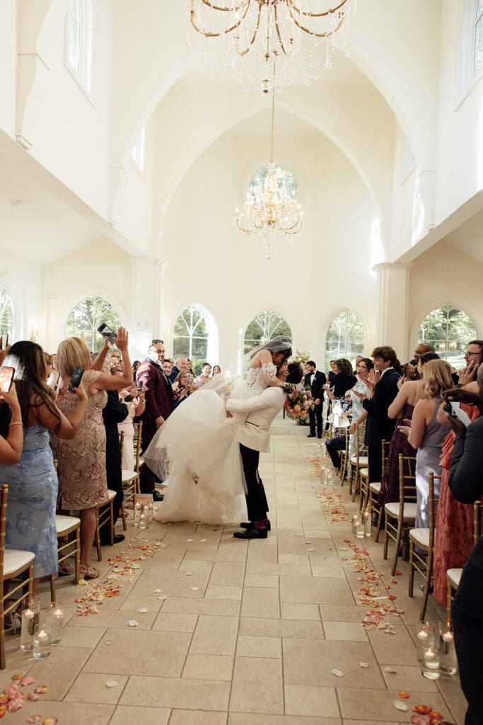 Groom lifting the bride for a kiss in their aisle after their Nanina's in the Park wedding ceremony inside The Chapel.