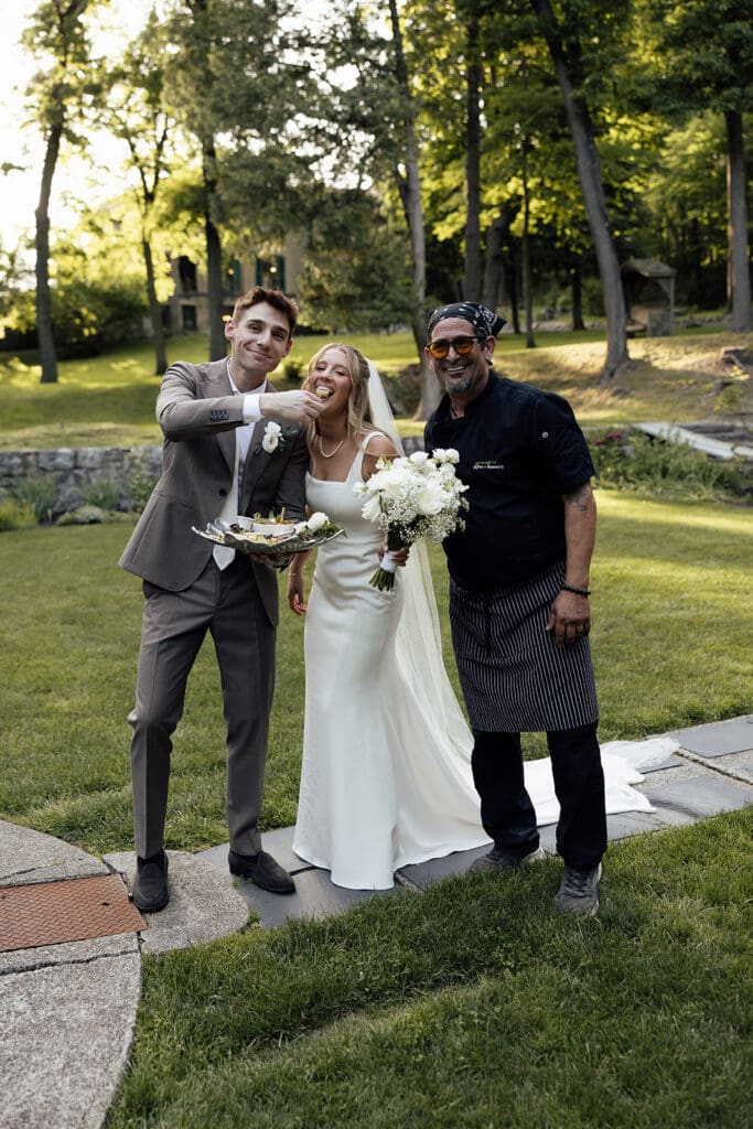 Brie and groom eating food and posing with their caterer, Love + Rosemary.
