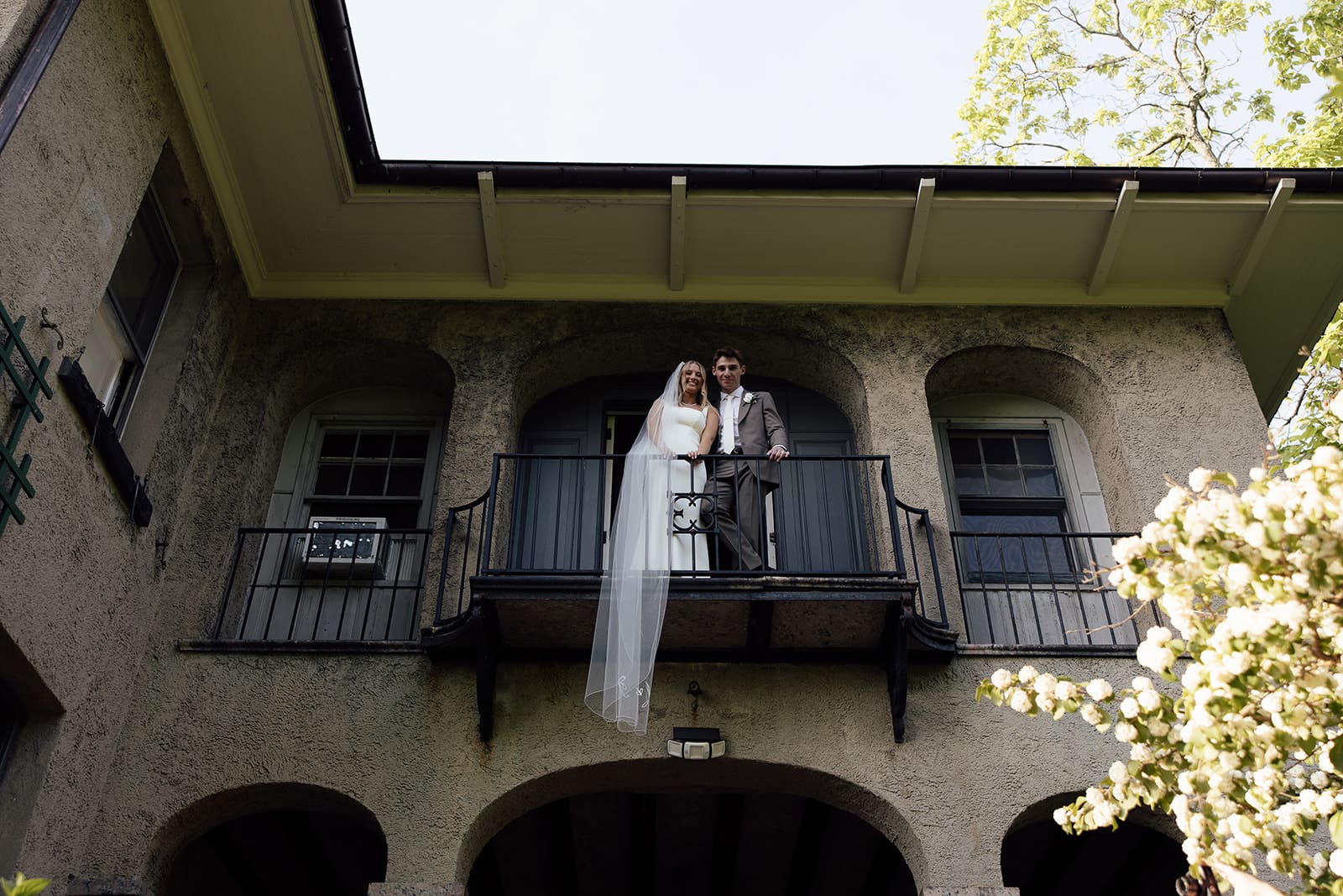 Bride and groom standing on a balcony off of The Mansion at Arrow Park wedding venue in Monroe, NY.