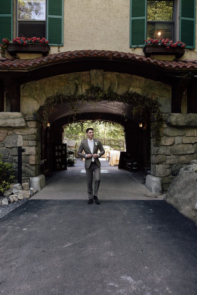 Groom walking outside of The Mansion at Arrow Park wedding venue.