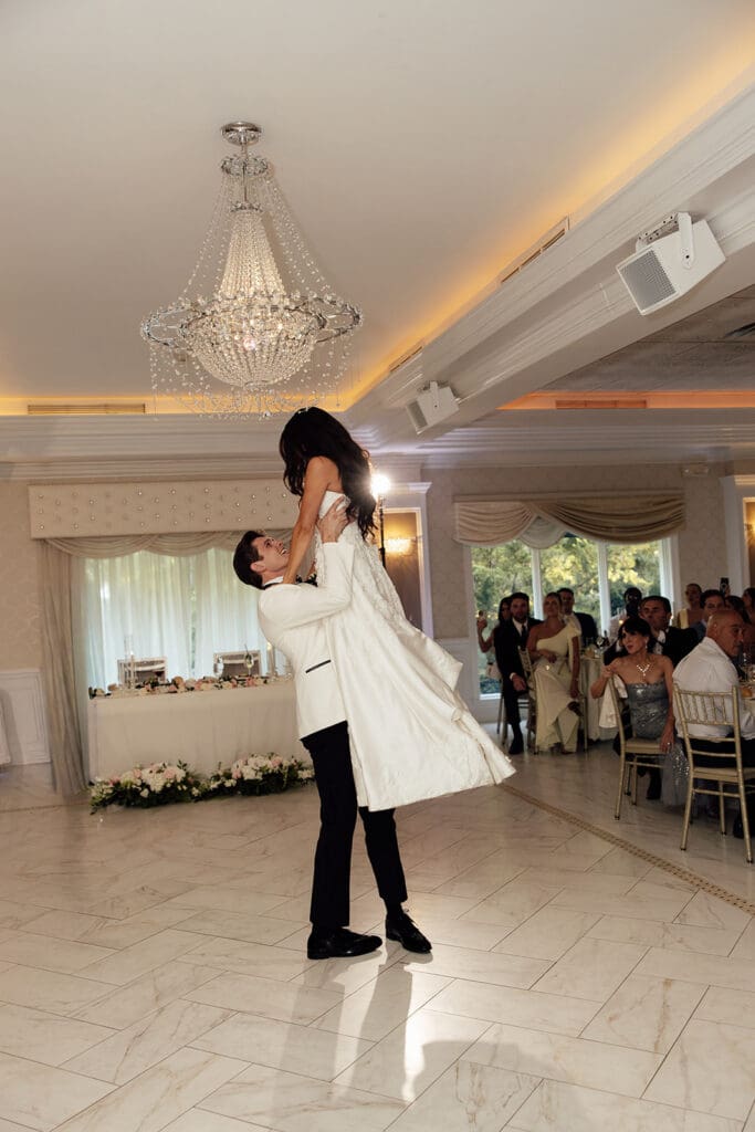 Groom lifting the bride in the air during their wedding reception in The Ballroom at The English Manor in Ocean, New Jersey. 