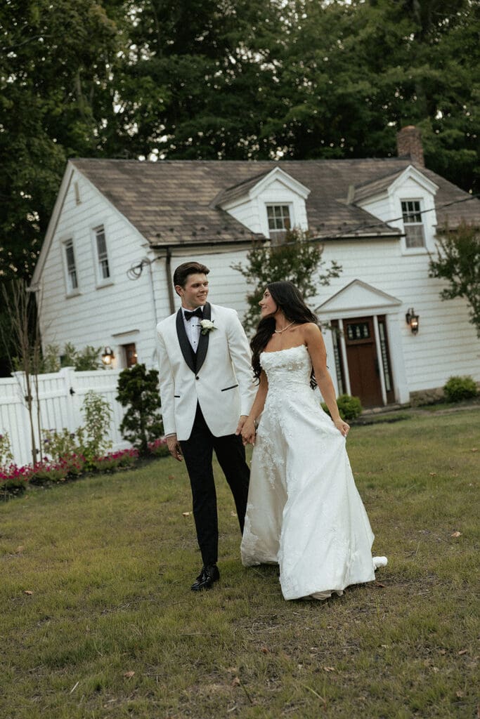 Bride and groom walking together in front of The English Manor in Ocean, New Jersey. 