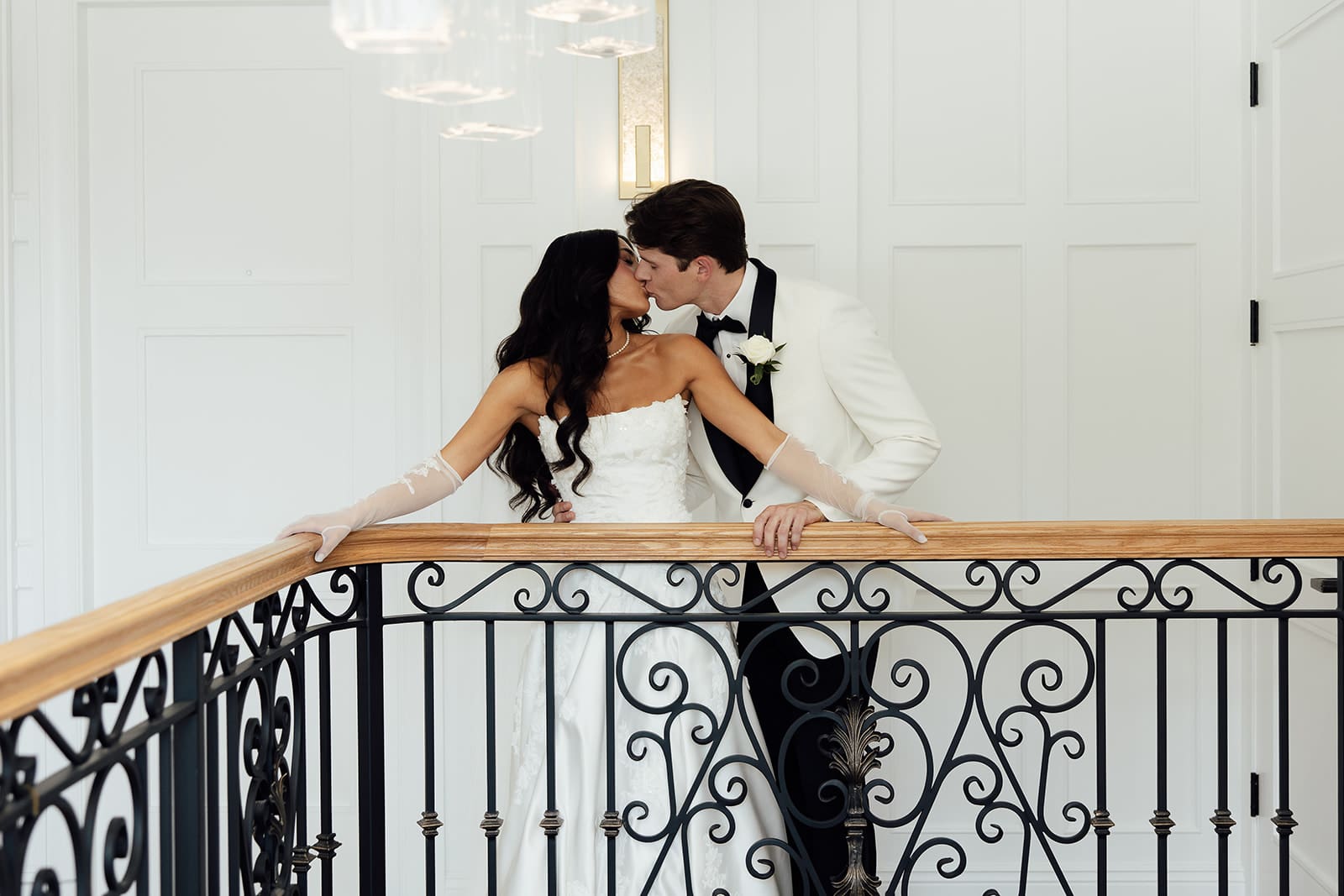 Bride and groom kissing as they pose against a railing inside The English Manor in Ocean, New Jersey. 